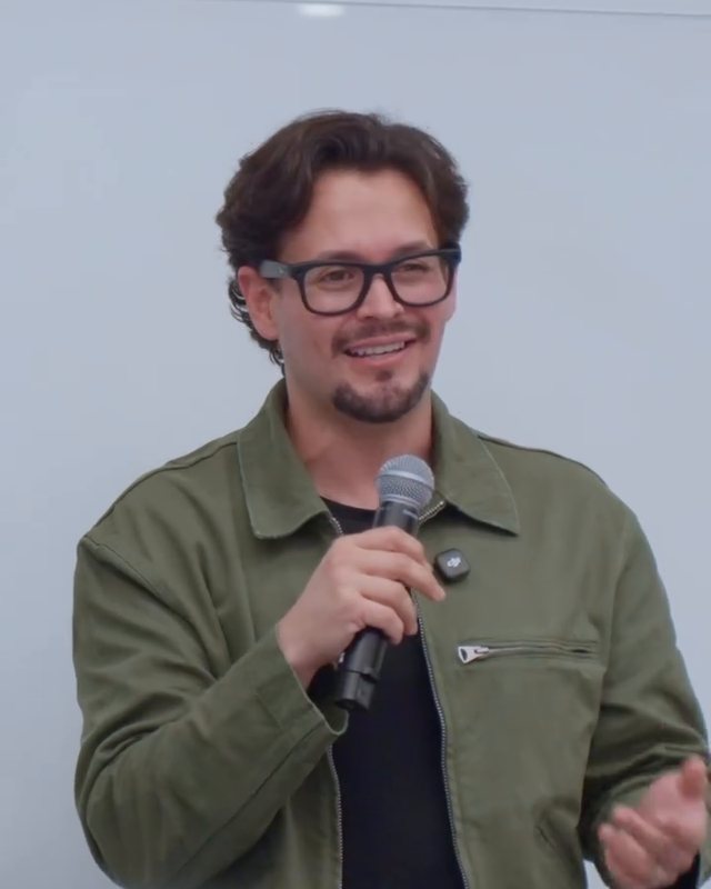 José Vásquez con micrófono, dando una charla